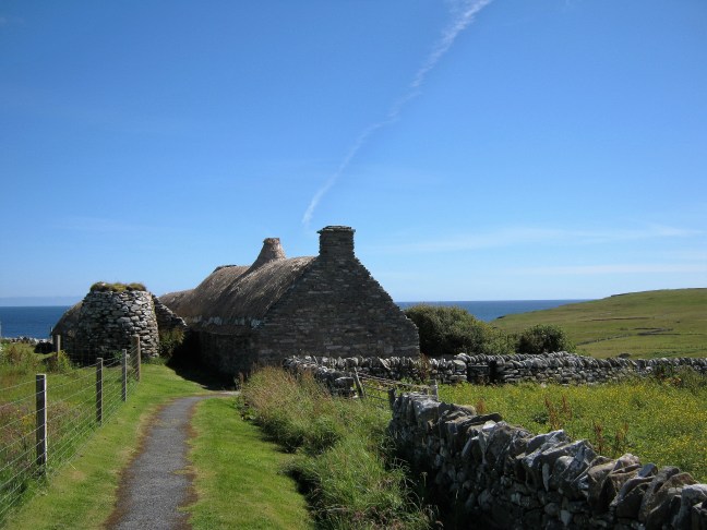 Thatched cottage on Shetland; blue sky, green fields
